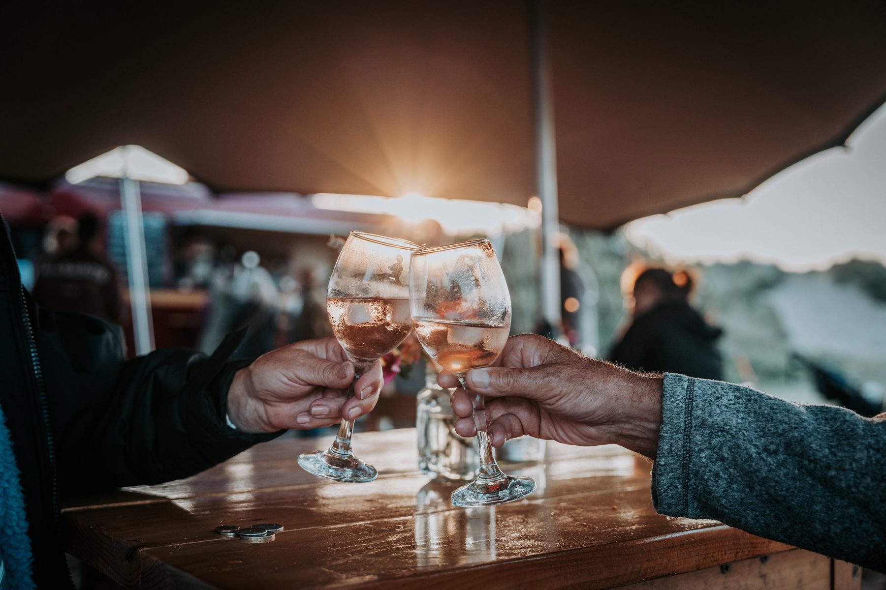Two glasses of rosé being clinked together under the canopy at dusk