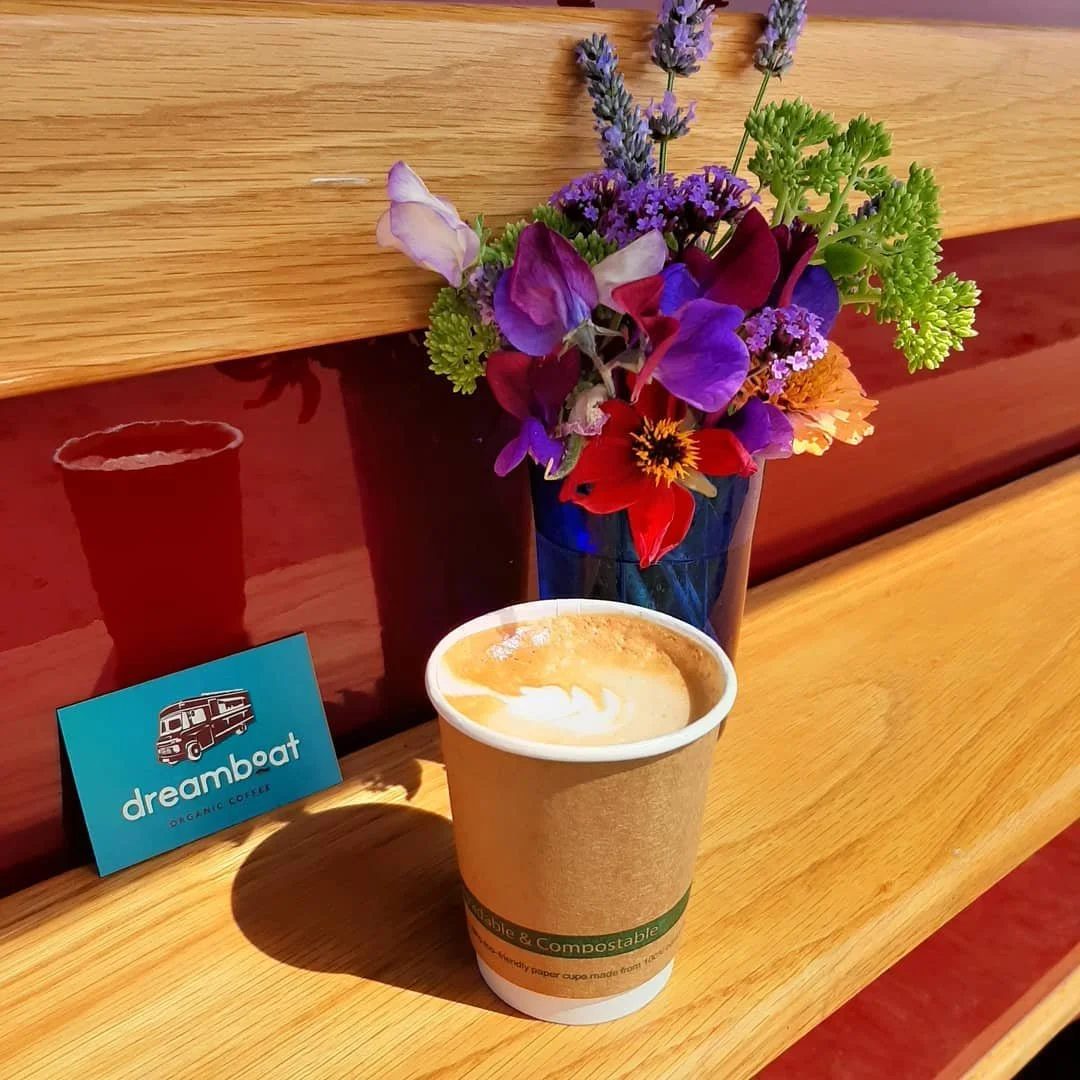 A Dreamboat turmeric latte in a compostable cup on the van's wooden shelf